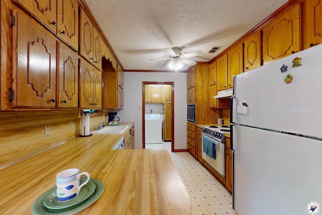 713 Franklin St, Texarkana, TX 75501 - kitchen with white appliances, washer / dryer, under cabinet range hood, ceiling fan, and brown cabinets