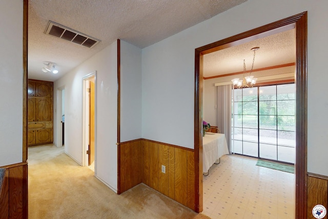 713 Franklin St, Texarkana, TX 75501 - hallway with a textured ceiling, wainscoting, a chandelier, wood walls, and light carpet