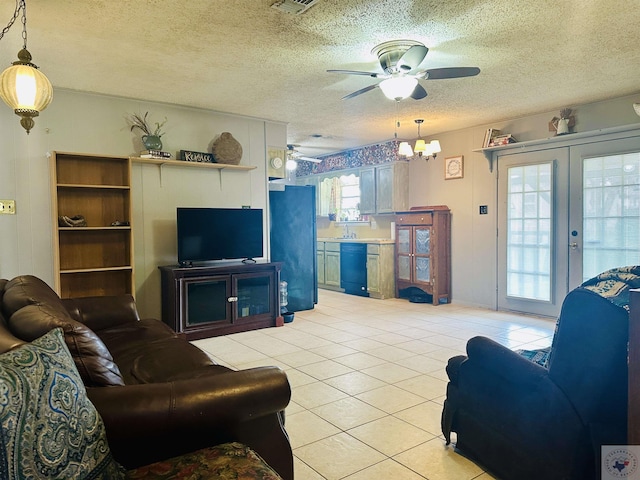 living area with french doors, visible vents, a ceiling fan, light tile patterned flooring, and a textured ceiling