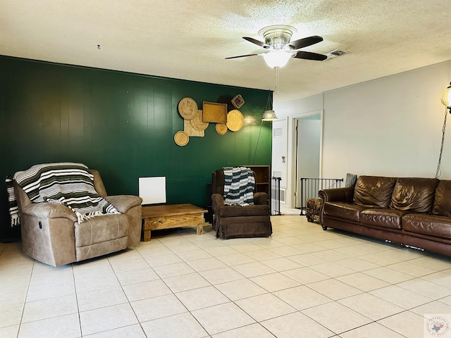 living area with light tile patterned floors, ceiling fan, visible vents, and a textured ceiling