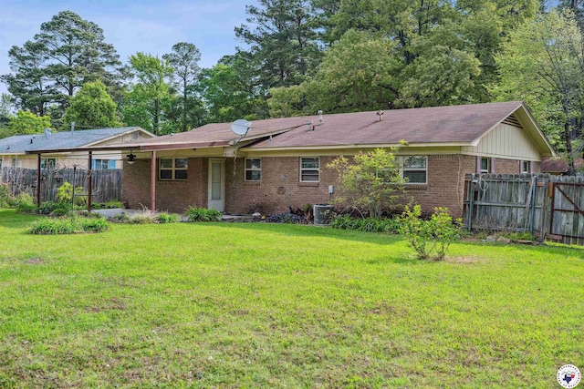 back of property featuring fence, brick siding, and a yard