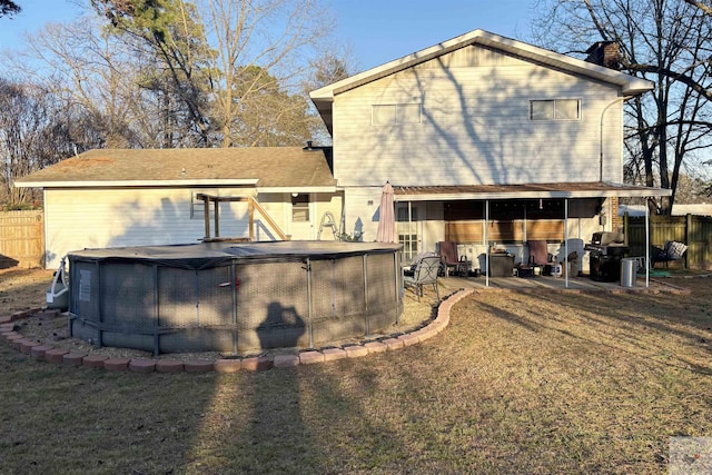 back of house with a yard and a covered pool