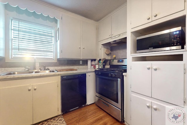 kitchen featuring appliances with stainless steel finishes, light wood-type flooring, white cabinets, and a textured ceiling