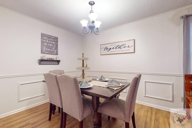 dining space featuring an inviting chandelier, wood-type flooring, crown molding, and a textured ceiling