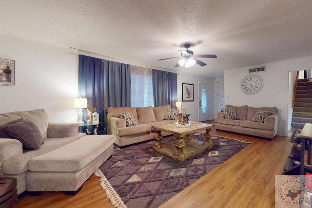 living room featuring ceiling fan, wood-type flooring, and a textured ceiling