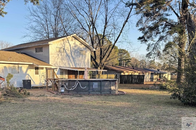 back of property with cooling unit, a fenced in pool, and a yard