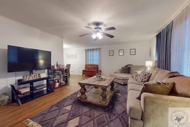 living room with ceiling fan, hardwood / wood-style flooring, and a textured ceiling