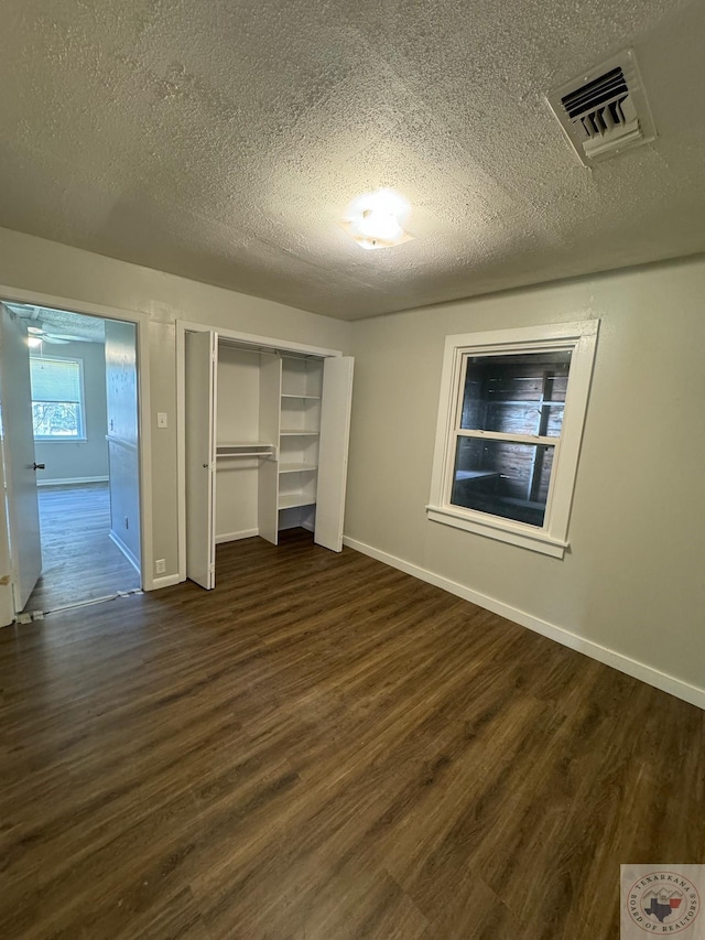 unfurnished bedroom with dark wood-type flooring, a textured ceiling, and a closet