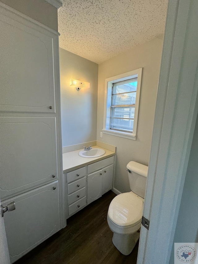 bathroom with vanity, toilet, a textured ceiling, and wood-type flooring