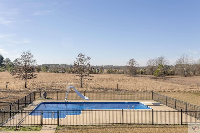 view of swimming pool featuring a rural view, a water slide, and a diving board