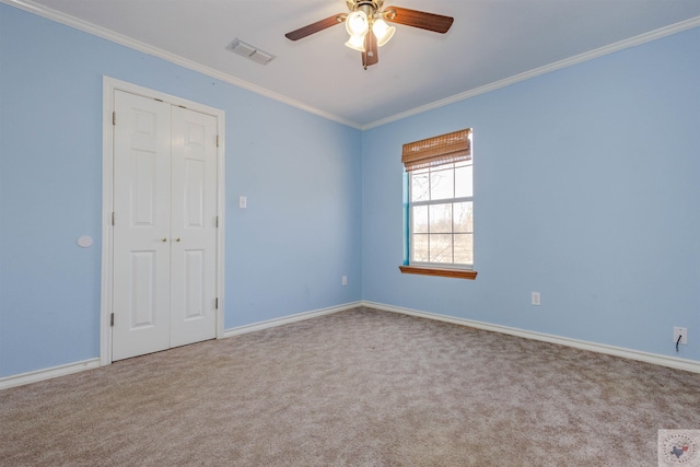 carpeted spare room featuring ceiling fan and ornamental molding