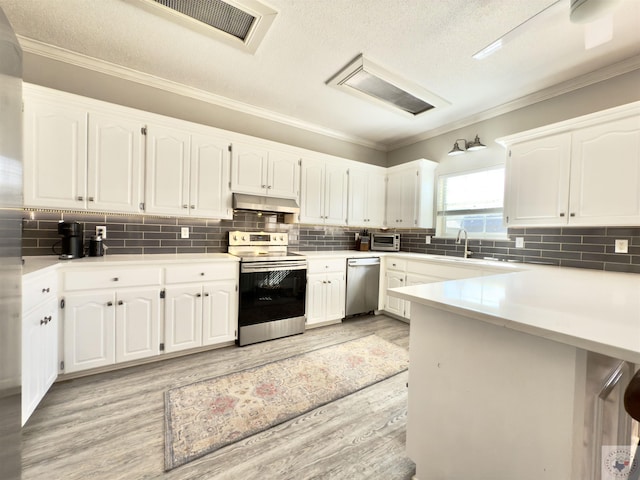 kitchen with white cabinets, appliances with stainless steel finishes, under cabinet range hood, and visible vents