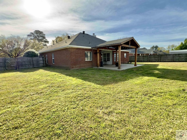 rear view of property featuring a fenced backyard, brick siding, a yard, and a patio