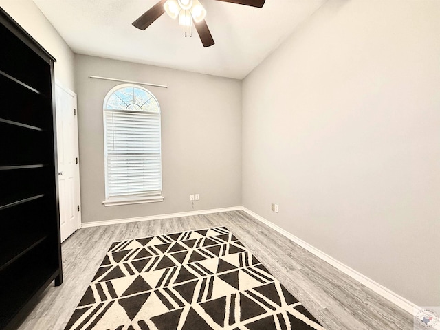 empty room with baseboards, light wood finished floors, and ceiling fan
