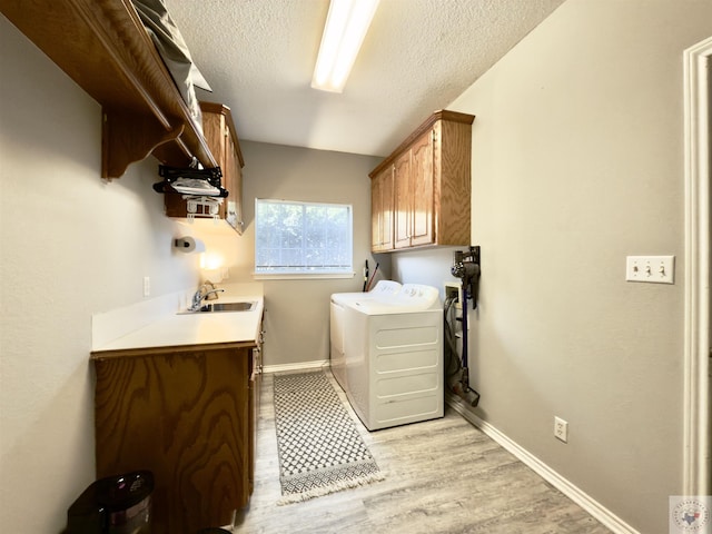 clothes washing area featuring baseboards, washer and dryer, cabinet space, and a sink