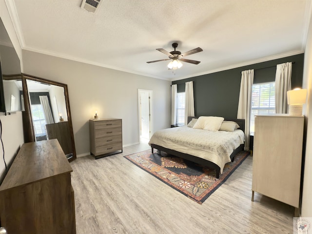 bedroom featuring crown molding, a textured ceiling, light wood-style floors, and visible vents