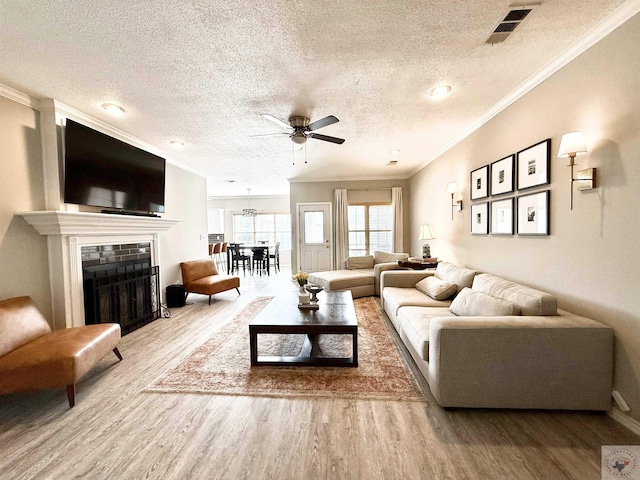 living area with visible vents, wood finished floors, ornamental molding, and a fireplace