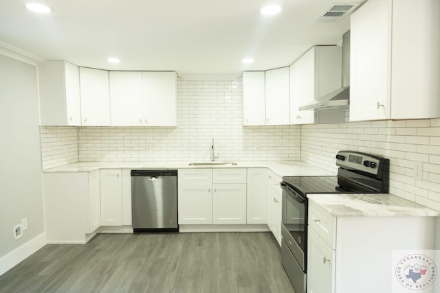 kitchen with light hardwood / wood-style floors, tasteful backsplash, white cabinets, sink, and stainless steel appliances