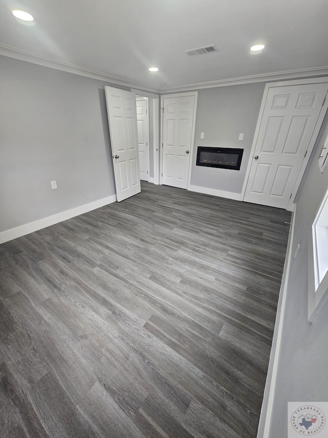 unfurnished living room featuring dark hardwood / wood-style flooring and crown molding