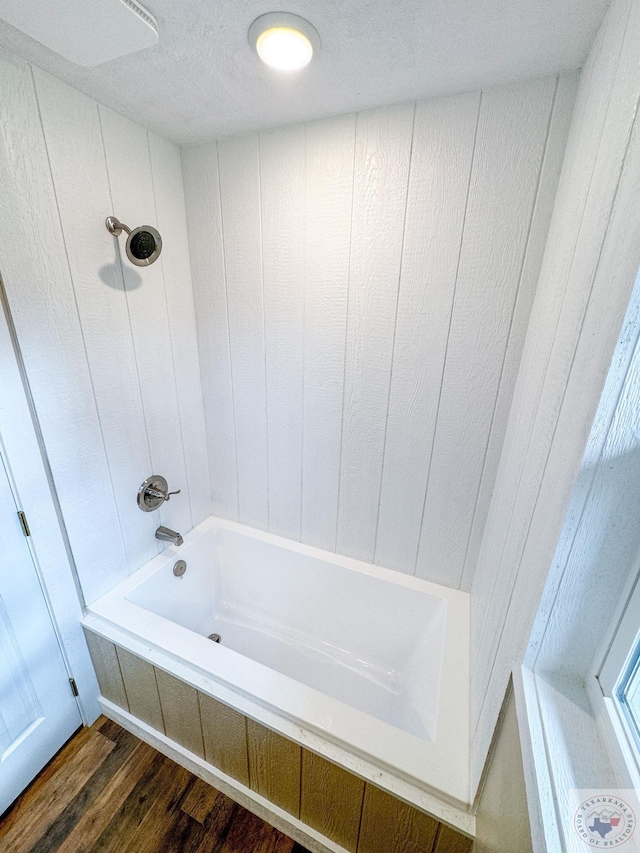 bathroom with bathing tub / shower combination and hardwood / wood-style floors