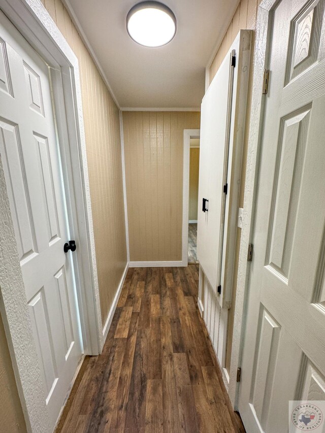 hall featuring crown molding, wood walls, and dark hardwood / wood-style floors