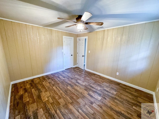 unfurnished bedroom featuring crown molding, wooden walls, dark hardwood / wood-style floors, and ceiling fan