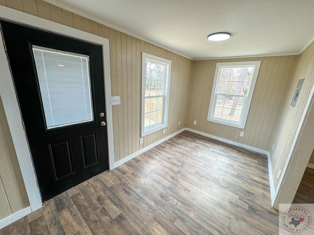 entryway featuring wood-type flooring, wooden walls, and ornamental molding