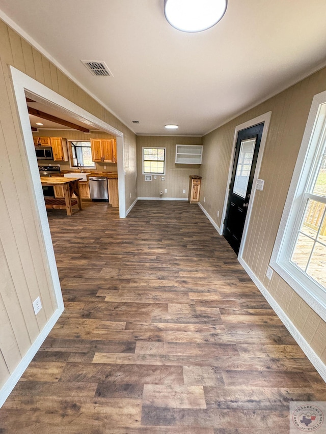 unfurnished living room featuring dark wood-type flooring and ornamental molding