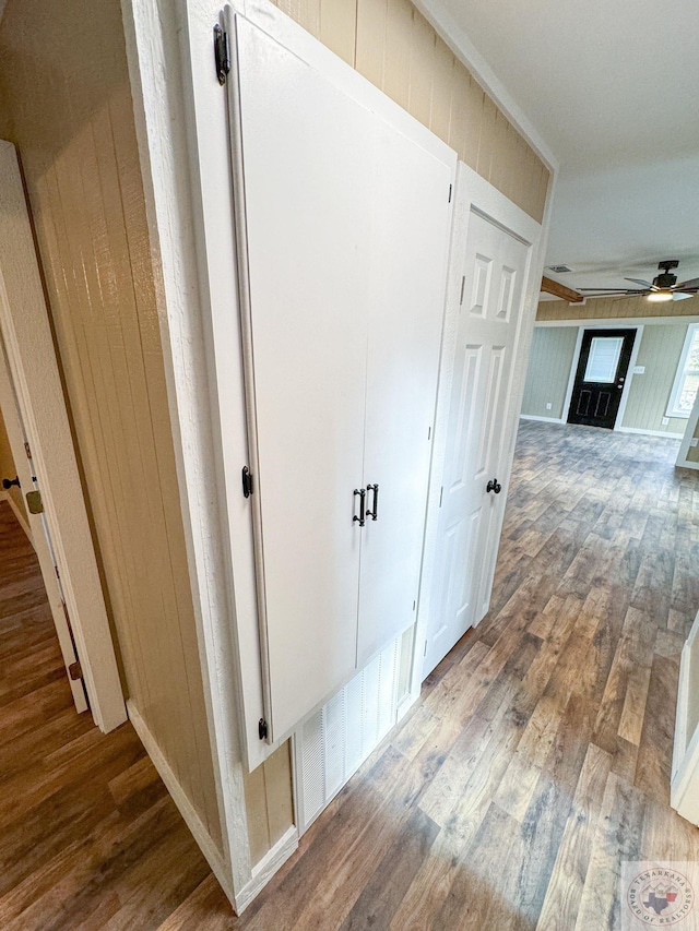 corridor with hardwood / wood-style flooring and wood walls