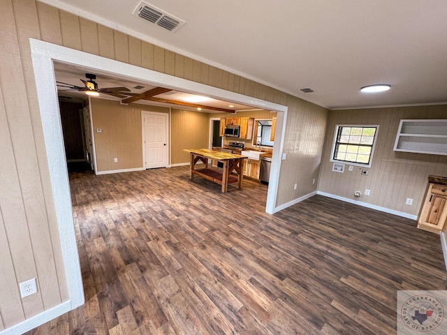 unfurnished living room featuring ceiling fan, dark hardwood / wood-style floors, and ornamental molding