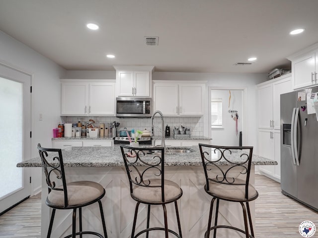 43 Broadmoor Dr, Texarkana, AR 78154 - kitchen with stainless steel appliances, white cabinetry, light wood-style floors, tasteful backsplash, and recessed lighting