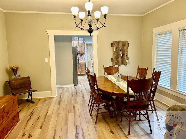 dining space featuring light hardwood / wood-style floors, a wealth of natural light, ornamental molding, and an inviting chandelier