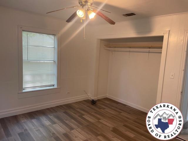 104 Pecan St, Atlanta, TX 75551 - unfurnished bedroom with crown molding, wood finished floors, baseboards, a ceiling fan, and a closet
