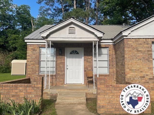 104 Pecan St, Atlanta, TX 75551 - property entrance with brick siding and metal roof