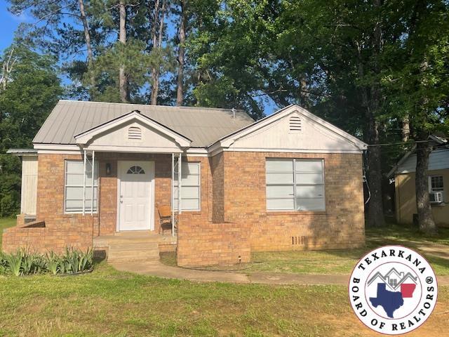 104 Pecan St, Atlanta, TX 75551 - ranch-style home with brick siding, a front yard, and metal roof