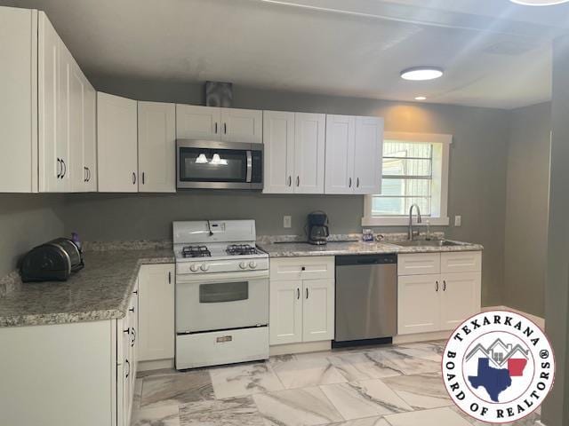 104 Pecan St, Atlanta, TX 75551 - kitchen featuring appliances with stainless steel finishes, light marble finish flooring, white cabinets, and recessed lighting