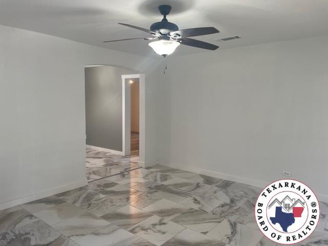 104 Pecan St, Atlanta, TX 75551 - spare room with ceiling fan, arched walkways, and baseboards