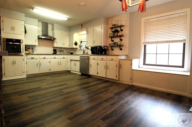 kitchen featuring wall chimney exhaust hood, backsplash, white cabinets, a textured ceiling, and stainless steel appliances