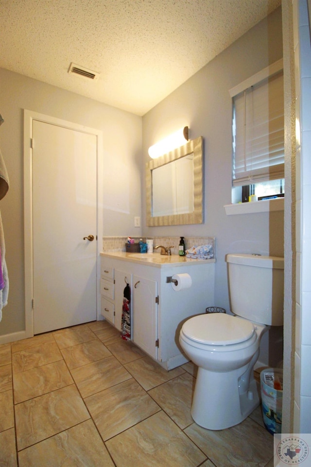 bathroom featuring toilet, a textured ceiling, and vanity