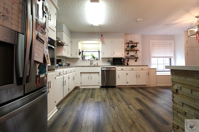 kitchen featuring a wealth of natural light, white cabinetry, sink, pendant lighting, and stainless steel appliances