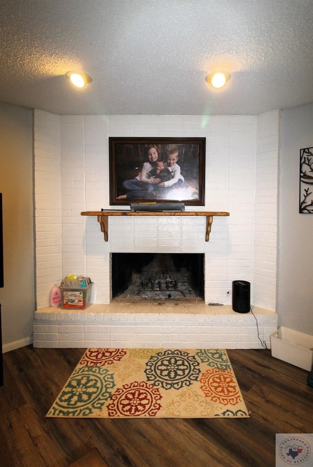 living room featuring a fireplace, dark wood-type flooring, and a textured ceiling