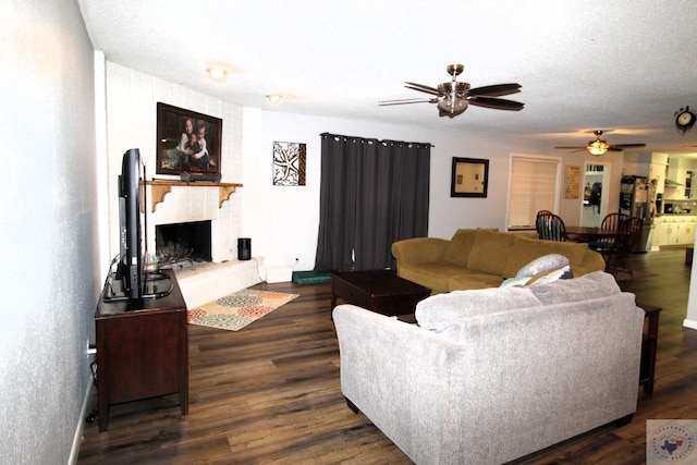 living room featuring ceiling fan, a textured ceiling, and dark hardwood / wood-style floors