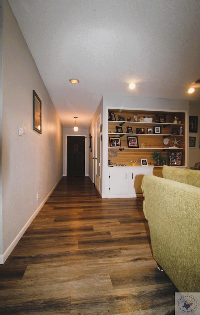 corridor with built in features, a textured ceiling, and dark hardwood / wood-style floors