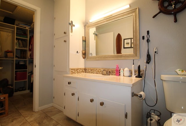 bathroom with toilet, decorative backsplash, tile patterned flooring, and vanity