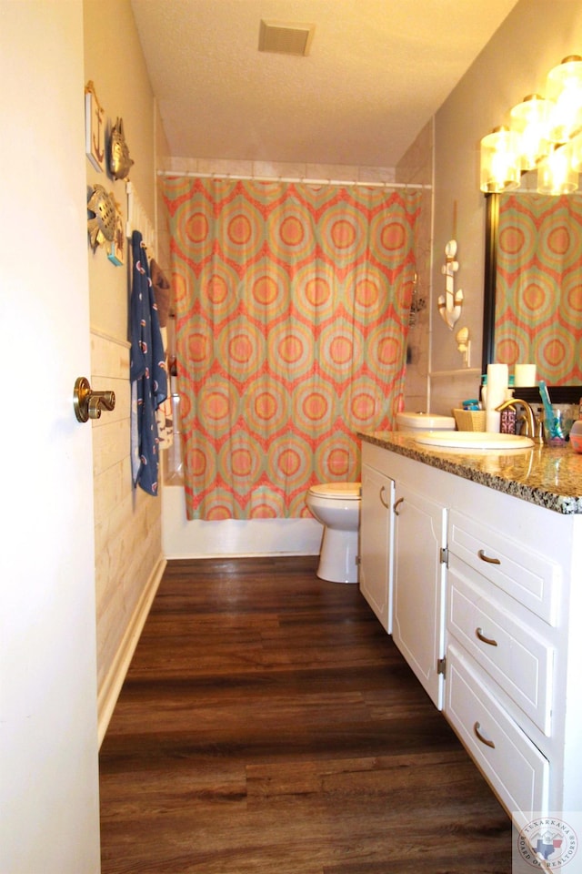 full bathroom featuring vanity, hardwood / wood-style flooring, shower / bath combo with shower curtain, and toilet