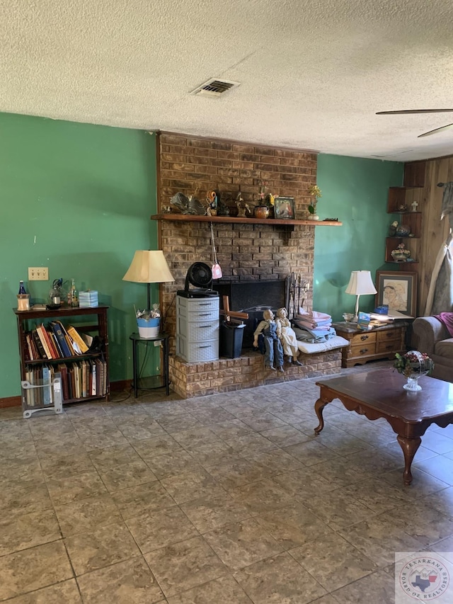 living room featuring ceiling fan, a textured ceiling, and a fireplace