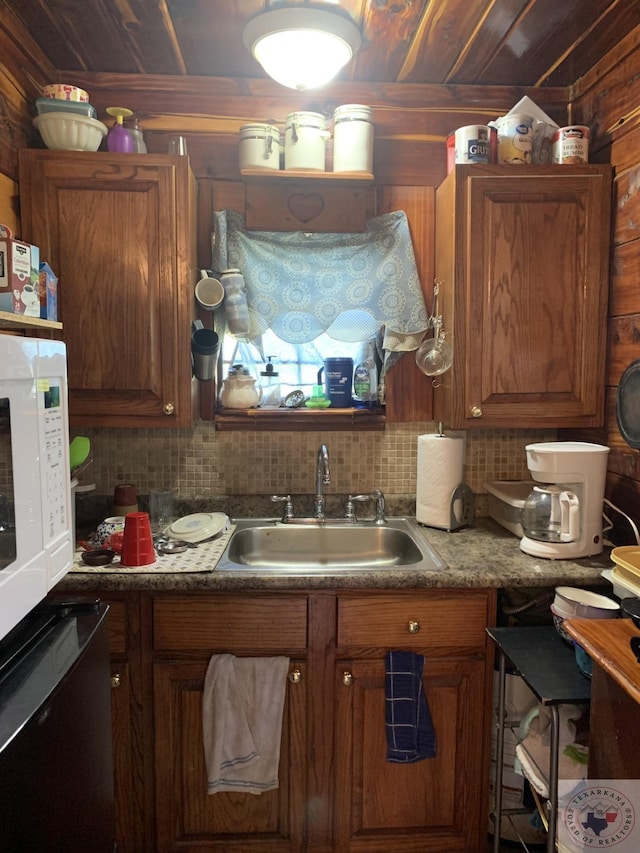 kitchen with sink, dishwashing machine, wood walls, and decorative backsplash