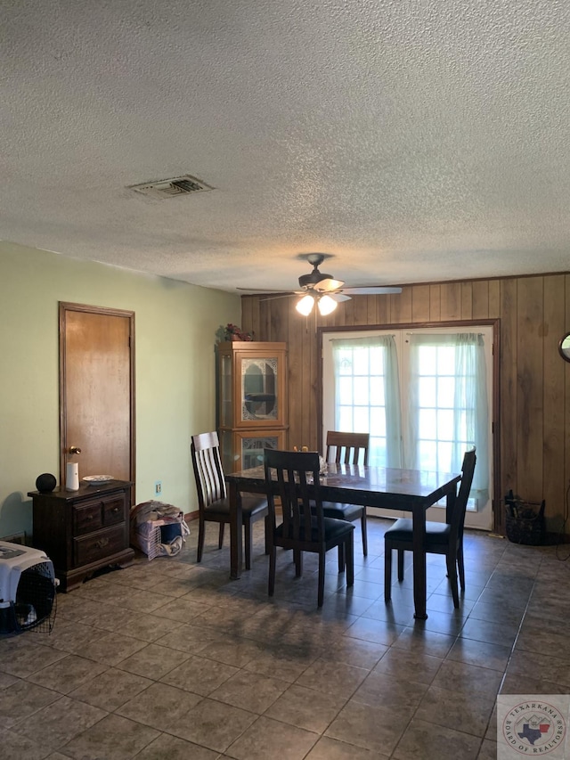 dining room with ceiling fan and wood walls