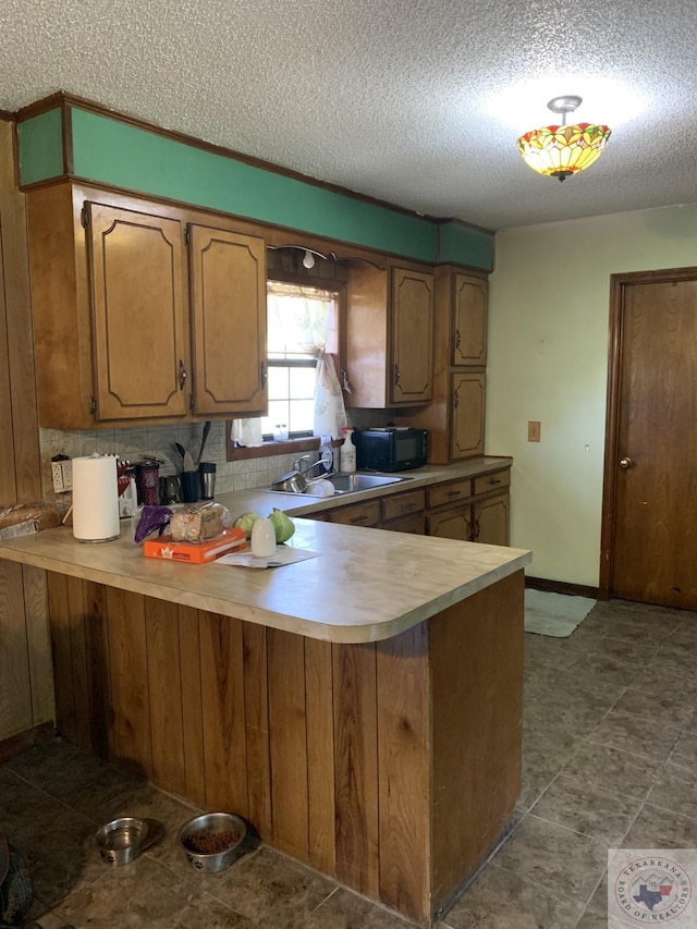 kitchen with sink, kitchen peninsula, and a textured ceiling