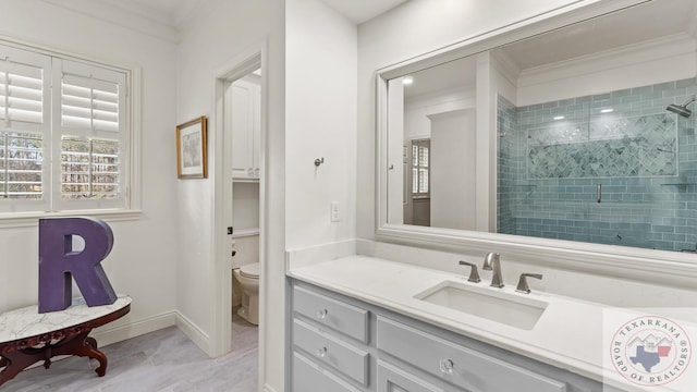 full bath featuring toilet, ornamental molding, a shower stall, vanity, and baseboards